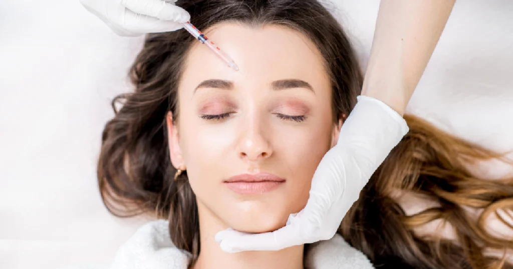 Current image: Woman receiving forehead injection while lying down, representing Neuromodulators in Richmond, KY for non-surgical wrinkle reduction and facial rejuvenation.